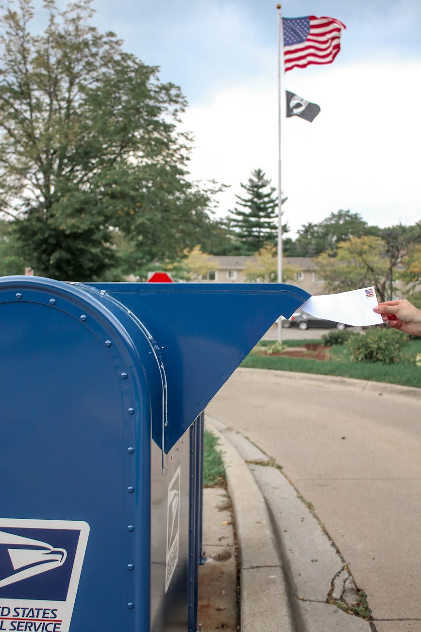 Trump Follows Putin’s Lead—Wants Mail‑In Voting Banned 1 crop person putting envelope in mailbox on street