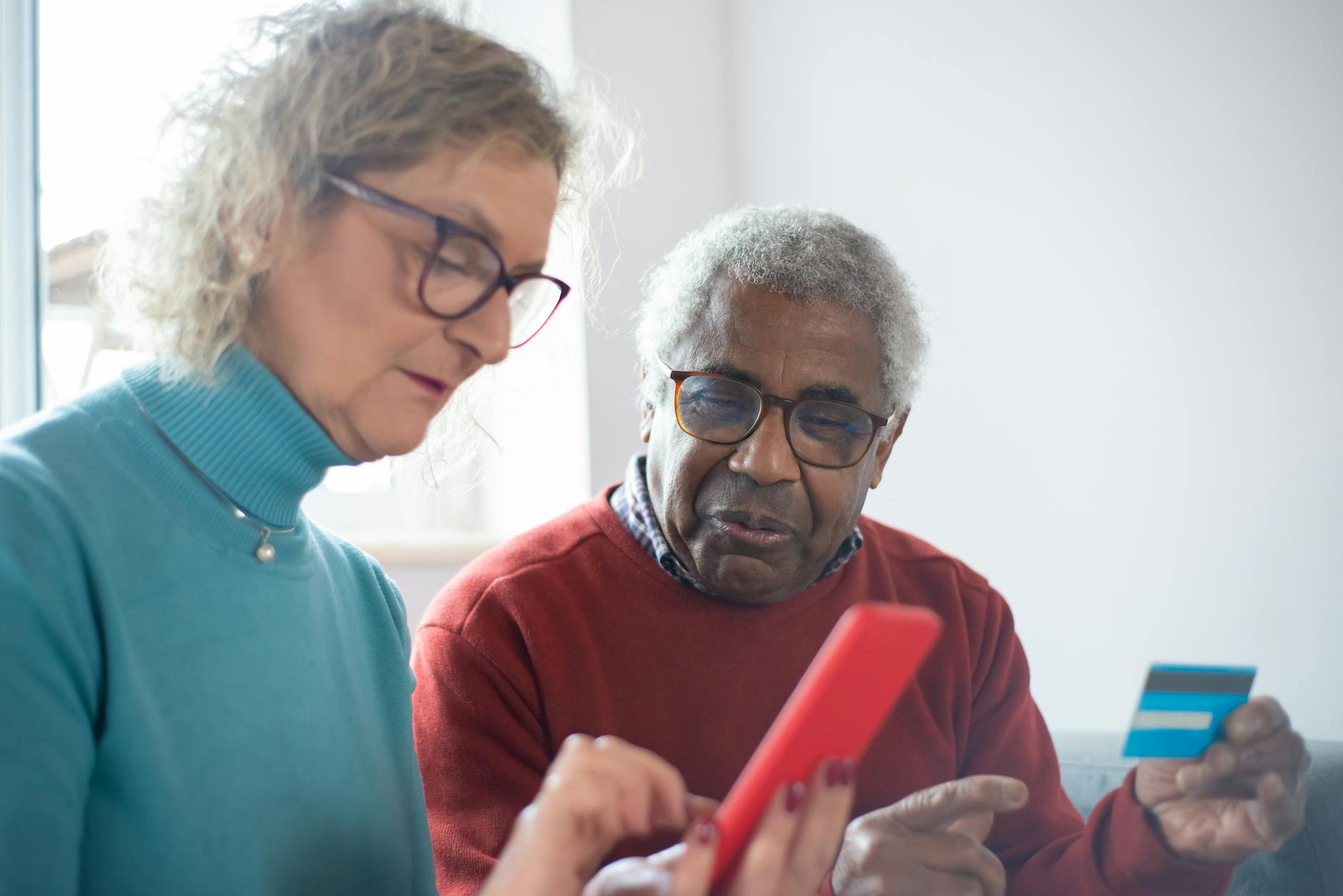 Minority health and aging - man holding a credit card and woman using a cellphone